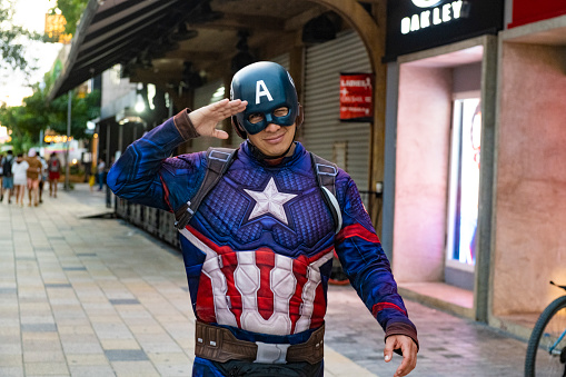 In Playa del Carmen, Mexico a street performer dressed as Captain America salutes as he walks by along Avenida Quinta.