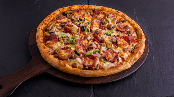 Beef Supreme pizza isolated on cutting board top view on dark background italian fast food