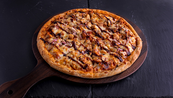 BBQ CHICKEN pizza isolated on cutting board top view on dark background italian fast food