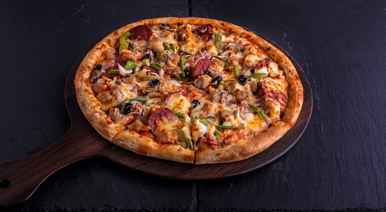 Chicken Supreme pizza isolated on cutting board top view on dark background italian fast food