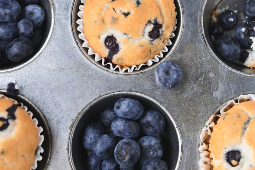 Flat lay of blueberry muffins and blueberries on dark table