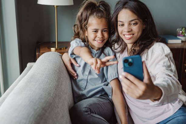 istock Mom and smiling little daughter using smart phone at home 1447482863