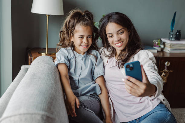 istock Mom and smiling little daughter using smart phone at home 1447482982