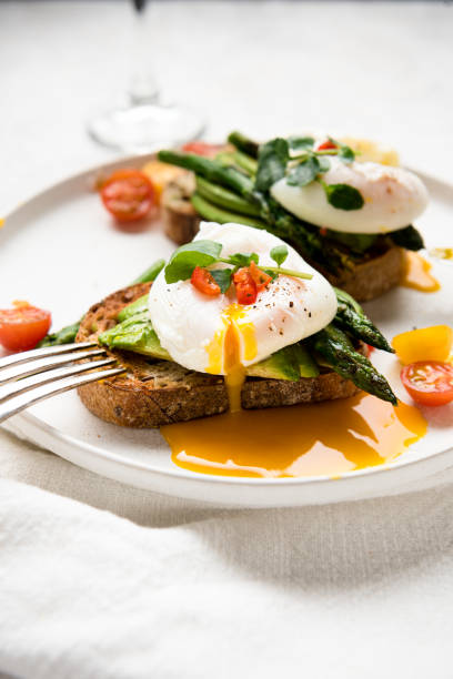 Poached eggs on toast with avocado, asparagus, tomatoes and sprout for healthy breakfast stock photo
