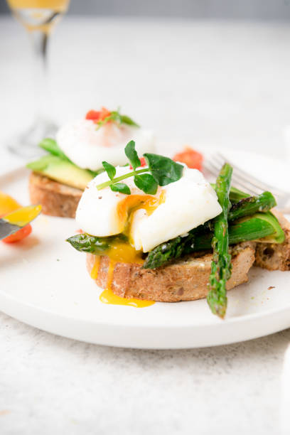 Poached eggs on toast with avocado, asparagus, tomatoes and sprout for healthy breakfast.