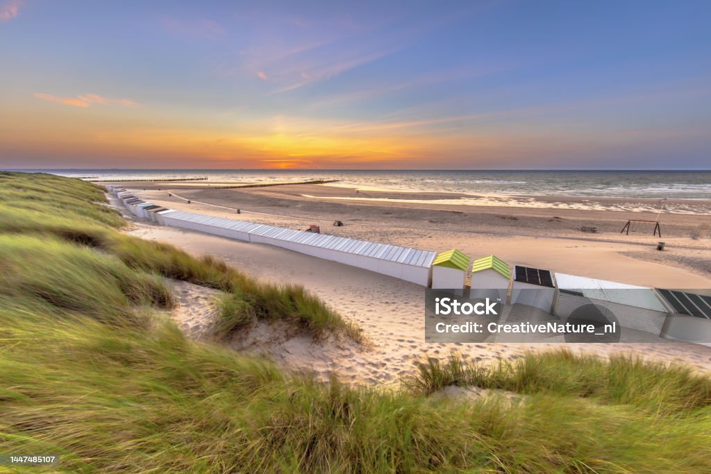 Row of beach houses in Zeeland Netherlands Beach houses on Westkapelle beach seen from the dunes in Zeeland at sunset, Netherlands. Landscape scene of nature in Europe. Schiermonnikoog Stock Photo