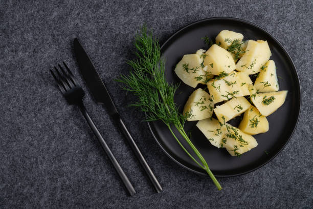 istock Boiled potatoes and dill on a black plate on a dark background 1447486992