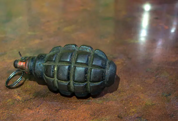 Fragmentation grenade with hole, on camouflage clothing. High quality photo