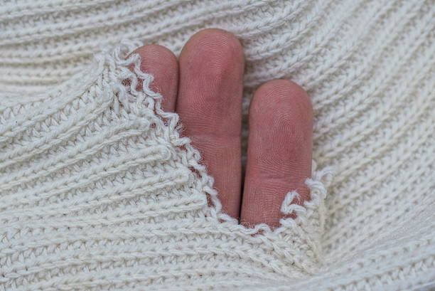 istock three brown fingers in a hole in torn white woolen fabric 1447493265