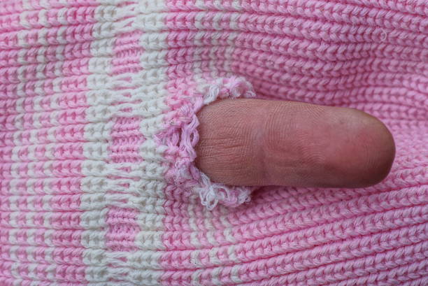 istock brown finger in a hole in torn white pink woolen fabric 1447493300