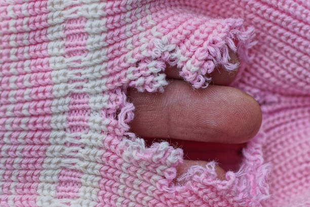 istock brown finger in a hole in torn white pink woolen fabric 1447493301