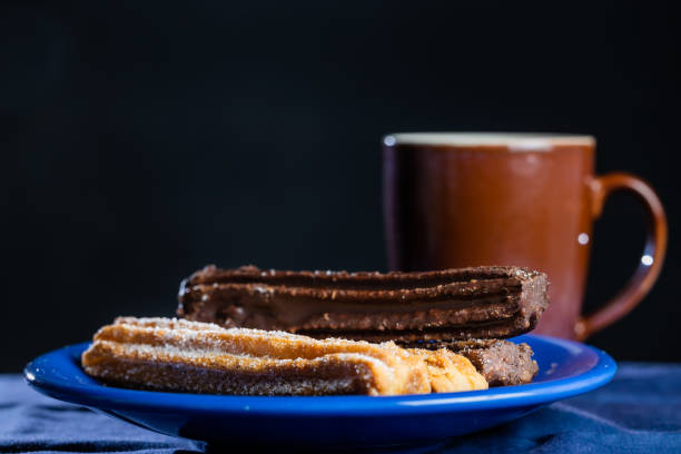 Typical Argentine churros with a cup of coffee on dark background.