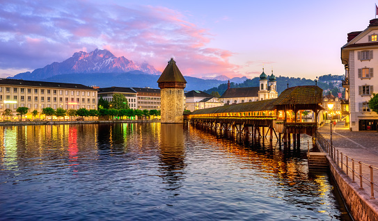 Lucerne city, Switzerland, view of Mount Pilatus, wooden Chapel bridge, the Water Tower and Old town on dramatical sunset