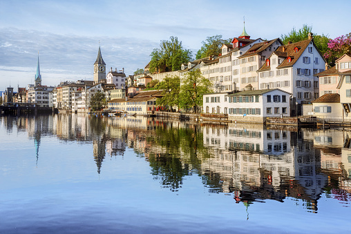 Zurich city's historical Old town center, traditional white houses in Schipfe quartier reflecting in Limmat river in the early morning light, Switzerland