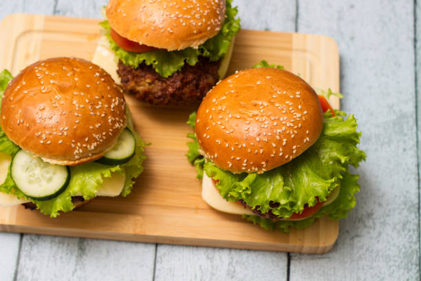 istock Delicious burgers with lettuce and cheese served on cutting board 1447509232