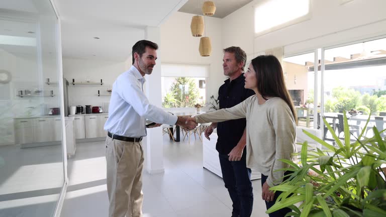 Caucasian couple looking at an open house property and talking to real estate agent handshaking