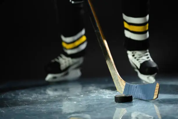 Photo of Hockey player in sports uniform and skates standing with stick in his hands.