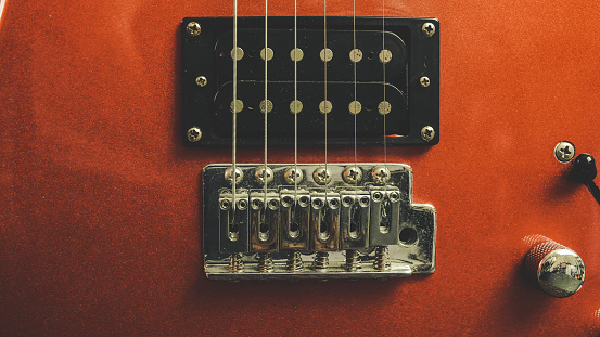 Main body, fretboard, bridge, tuner and pick up accent of a red electric guitar. macro shot and vintage.