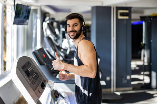 istock A young man is running on a treadmill in a gym showing a thumb up. 1447520521