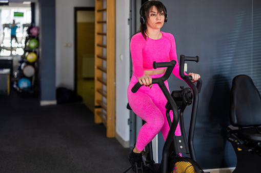 A female is doing exercise training in a gym using a bike for practicing.