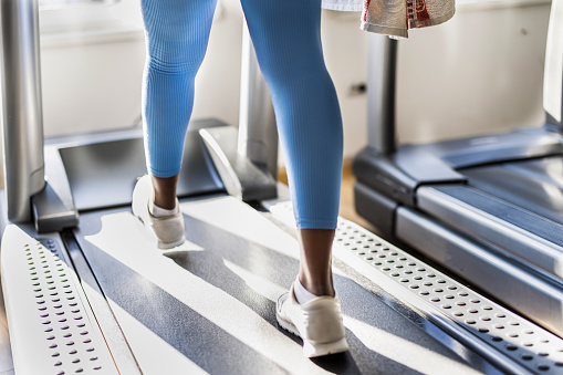 Close-Up view of woman's legs on a treadmill while exercising in a modern gym.