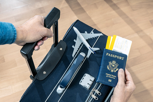 PASSENGER HOLDING USA PASSPORT, TWO BOARDING PASSES AND A SUITCASE AT THE AIRPORT READY TO FLY. TRAVEL INSURANCE FOR BUSINESS AND VACATIONS. SELECTED FOCUS.