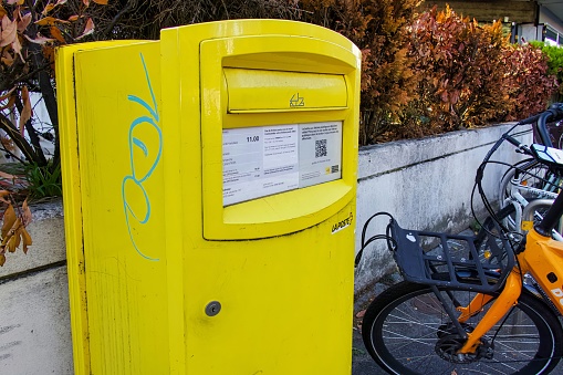 geneva, switzerland - 08 September 2022: a yellow letterbox of the swiss mail on the street to send envelopes and other mail