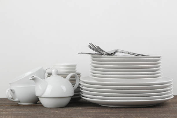 istock A stack of dishes. tableware on a brown wooden table. plates and cutlery, cups and kettle. 1447524798