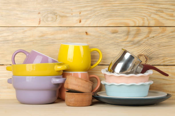 A stack of dishes. colored dishes on a natural wooden table. multi-colored cups and bowls.