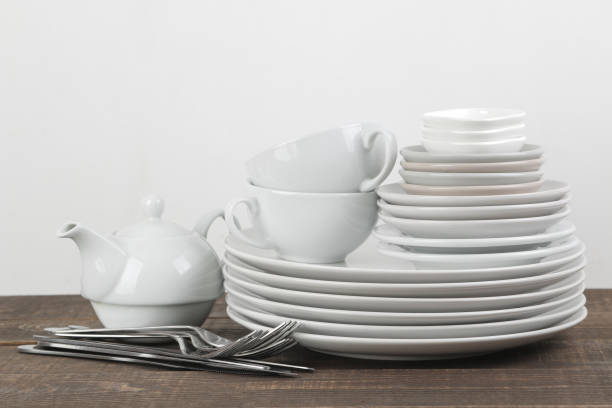 istock A stack of dishes. tableware on a brown wooden table. plates and cutlery, cups and kettle. 1447524828