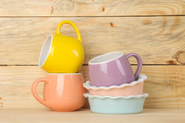 A stack of dishes. colored dishes on a natural wooden table. multi-colored cups and bowls.