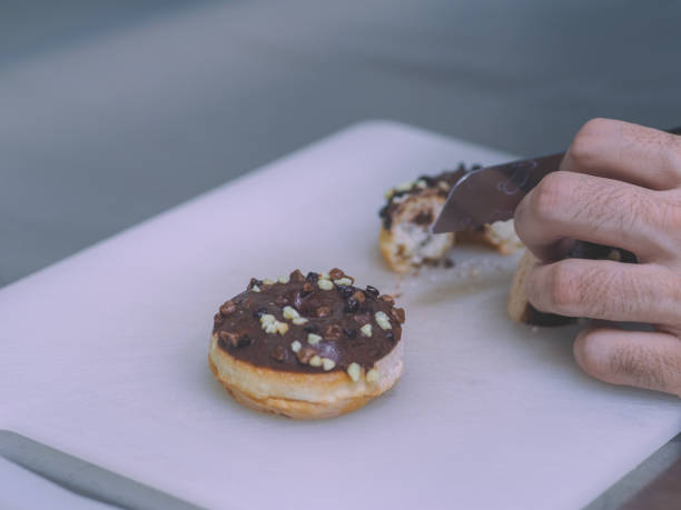 istock pastry chef cutting chocolated sparkled donut for cake decoration on kitchen board 1447525074