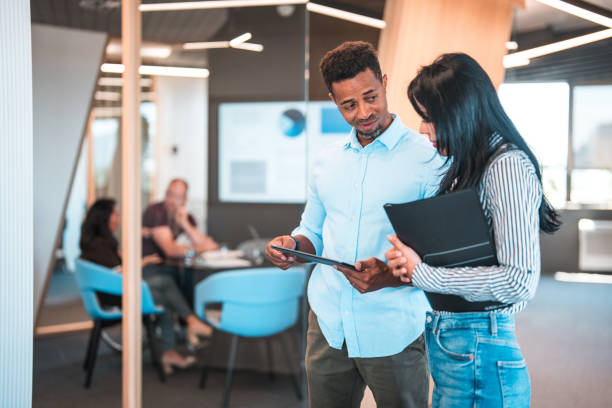 istock Hispanic Woman and Multi-ethnic Man Using Digital Tablet in Office Hallway 1447526506