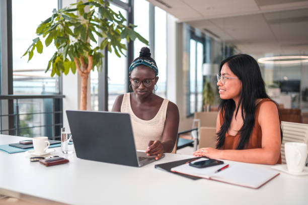 istock Beautiful Young Mixed Race Women Using A Laptop In A Modern Office 1447526573