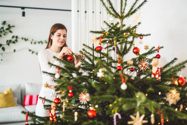 istock Woman decorating a huge natural Christmas tree putting on red ornaments 1447529732