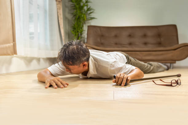 istock Asian senior man falling down and lying on the floor while walk with walking stick at home. 1447540812