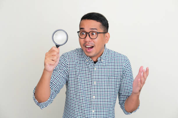istock Adult Asian man looking through magnifying glass with surprised expression 1447541169