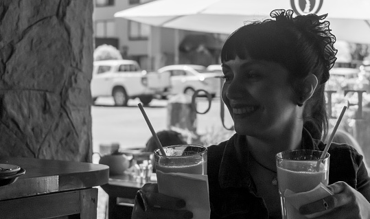 Black and white photo of waitress bringing glasses of orange juice to customers