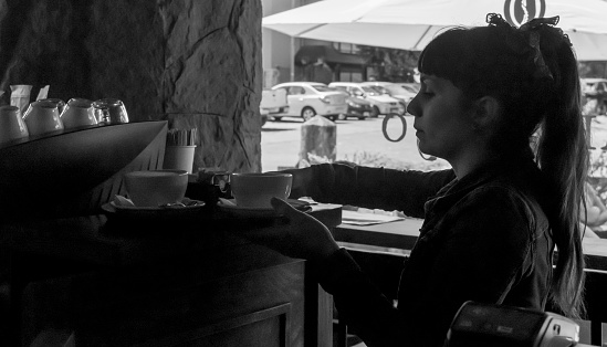 Black and white photo of waitress bringing coffee cup order to customers