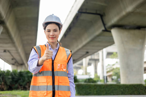 istock Asian engineer worker woman or architect looking construction with white safety helmet in construction site. Standing at highway concrete road site. Progress planning of highway bridge. 1447546553