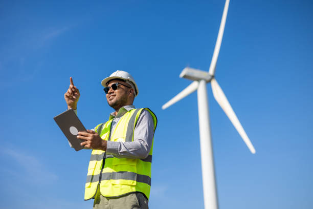 istock Engineer India man working with tablet at windmill farm Generating electricity clean energy. Wind turbine farm generator by alternative green energy. Asian engineer checking control electric power 1447546930