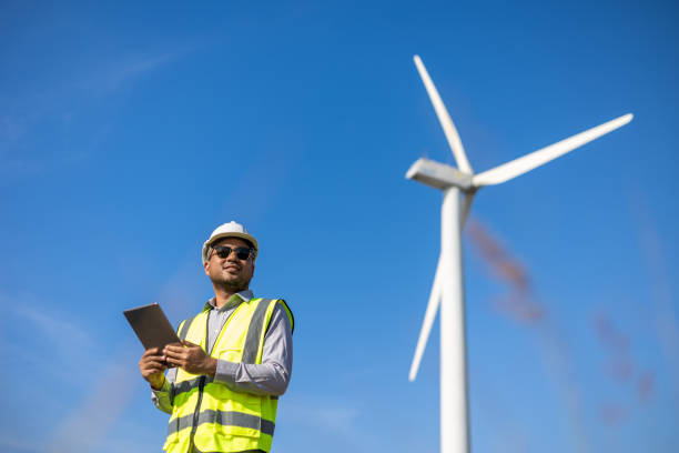 istock Engineer India man working with tablet at windmill farm Generating electricity clean energy. Wind turbine farm generator by alternative green energy. Asian engineer checking control electric power 1447547151
