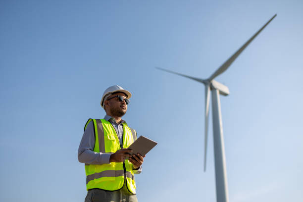istock Engineer India man working with tablet at windmill farm Generating electricity clean energy. Wind turbine farm generator by alternative green energy. Asian engineer checking control electric power 1447547831