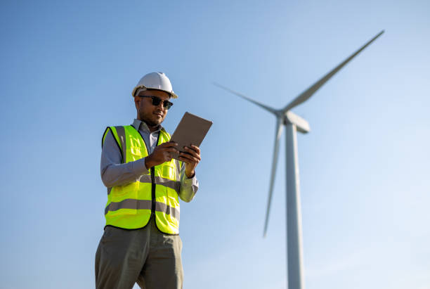 istock Engineer India man working with tablet at windmill farm Generating electricity clean energy. Wind turbine farm generator by alternative green energy. Asian engineer checking control electric power 1447547833
