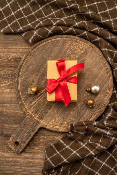 istock Christmas present on wooden cutting board with Christmas decorations. 1447554885
