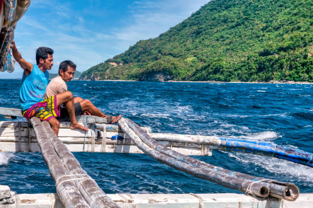 deux membres de l’équipage local de la banca montent sur un stabilisateur tout en conduisant le long de l’île de mindoro, aux philippines. - motoring photos et images de collection