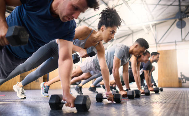 starke, fitness- und fitness-leute mit hantel-teamwork-training oder übung gemeinschaft, verantwortlichkeit und gruppe. sportliche vielfalt freunde auf dem boden in liegestützmuskeltraining, kraft und wellness zusammen - krafttraining stock-fotos und bilder