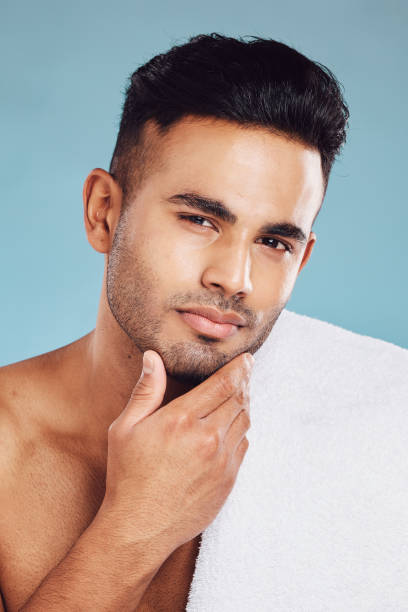 istock Hand, face and beauty with a man model posing in studio on a blue background for grooming or skincare. Portrait, luxury and wellness with a male indoors to promote a natural product or skin treatment 1447566888