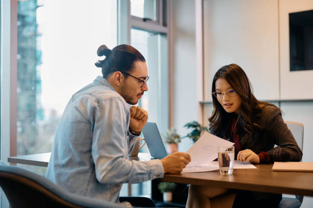 istock Young business colleagues cooperating while going through paperwork in the office. 1447566984