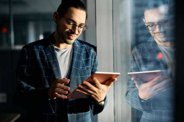 istock Happy Hispanic entrepreneur using touchpad by the widow in the office. 1447567143